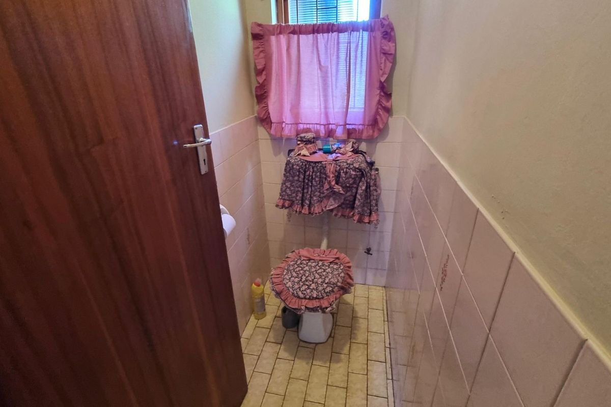A compact bathroom featuring a toilet with wall-mounted tiling and a window.