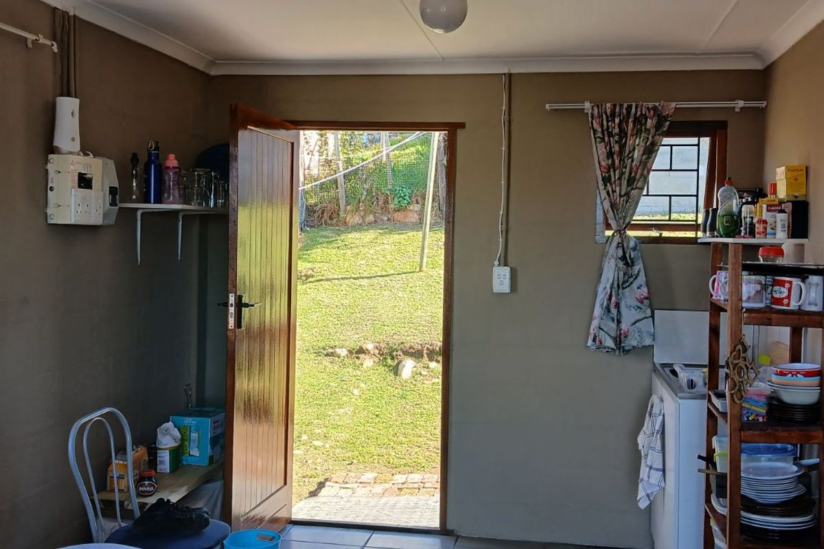 A functional utility or kitchen space featuring tiled flooring, exposed electrical conduit, and direct access to the rear garden area.