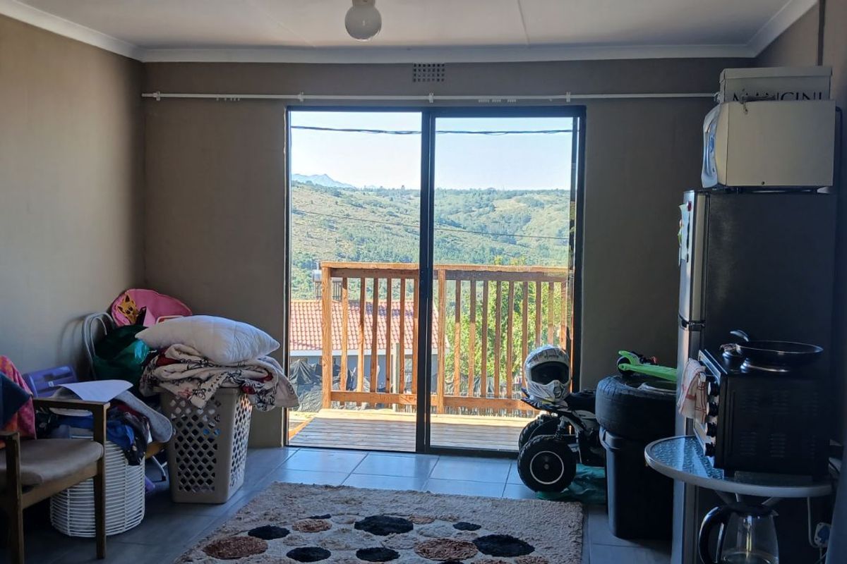 A living area featuring tiled flooring and large sliding glass doors that open onto a wooden balcony with scenic mountain views.