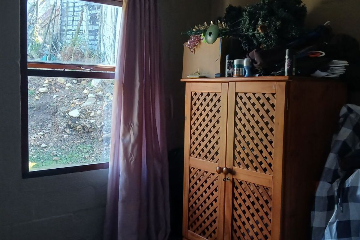 A bedroom featuring a window with exterior views and basic wall finishes.