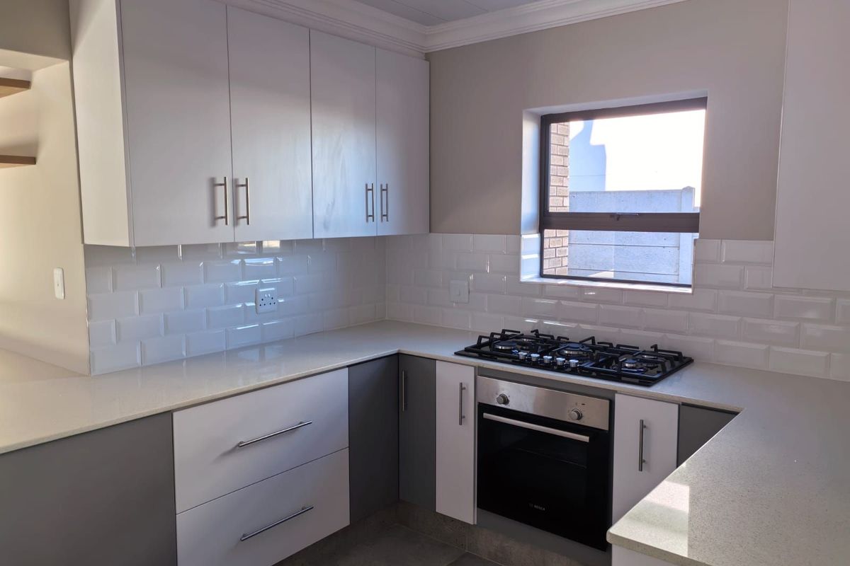 Modern kitchen featuring white and grey cabinetry, stone countertops, subway tile backsplash, and a built-in gas hob with oven.