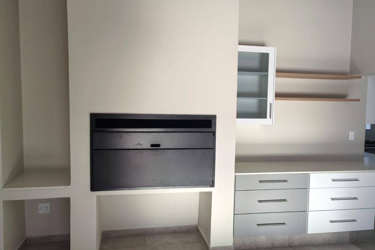 A modern built-in indoor braai area featuring sleek cabinetry, floating shelves, and tiled flooring, providing a functional and stylish entertainment space.