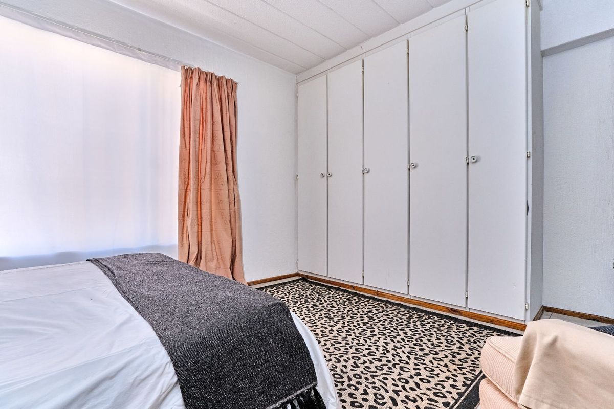 A bedroom featuring built-in floor-to-ceiling wardrobes and a window with natural light.