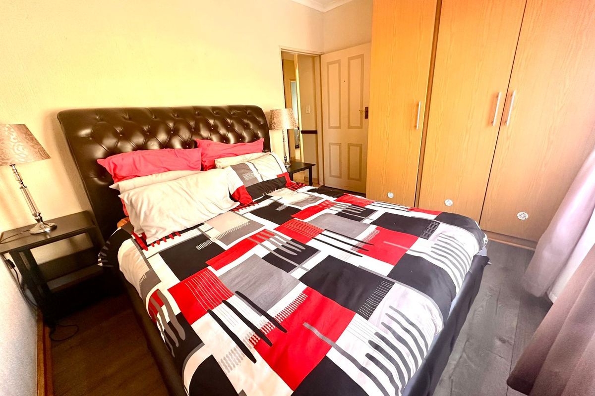 A bedroom featuring built-in wooden cupboards and laminate flooring, providing functional storage space within the townhouse.