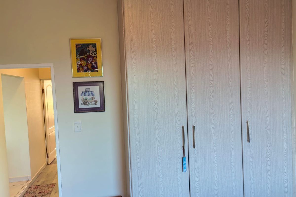 A bedroom interior featuring built-in wooden wardrobes with modern handles, providing ample storage space.
