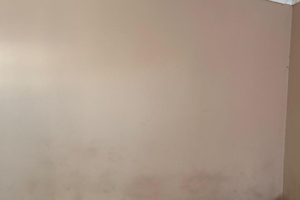 A bedroom wall showing significant surface staining and discoloration, indicating potential moisture or maintenance issues requiring attention.