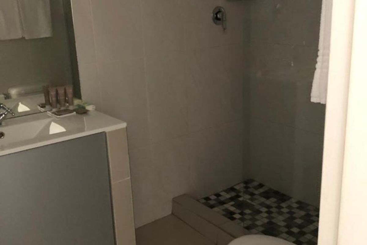 A functional bathroom featuring a walk-in shower with mosaic tile flooring, a vanity with integrated basin, and a standard toilet.