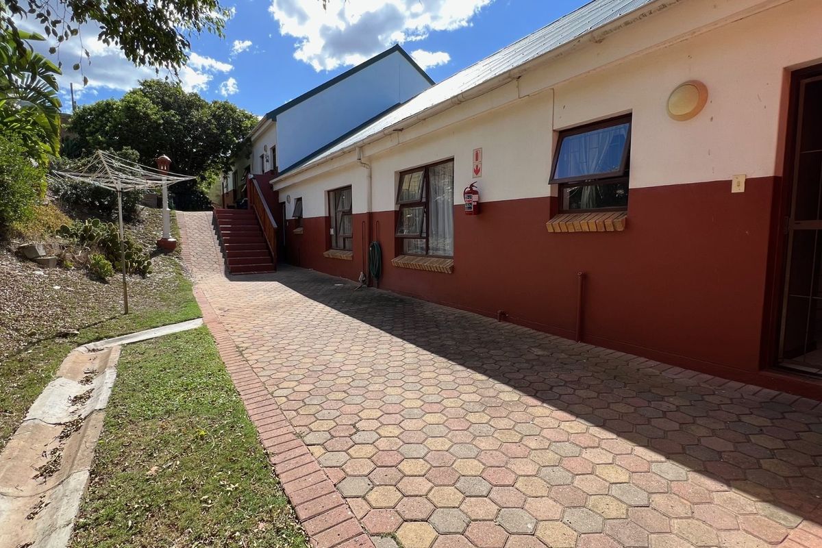 Exterior view of the apartment building featuring paved walkway, external staircase, and access to the rear garden area.