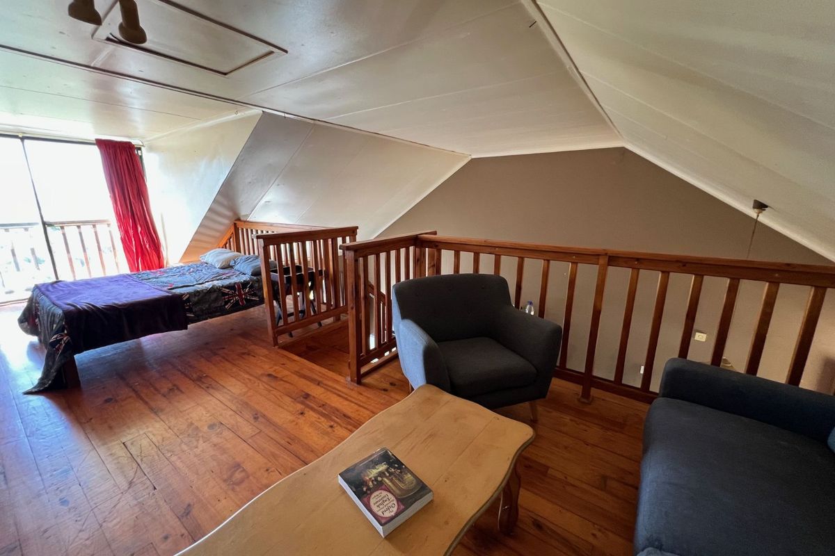 Loft-style bedroom featuring timber flooring, exposed wooden balustrades, and direct access to a balcony area.