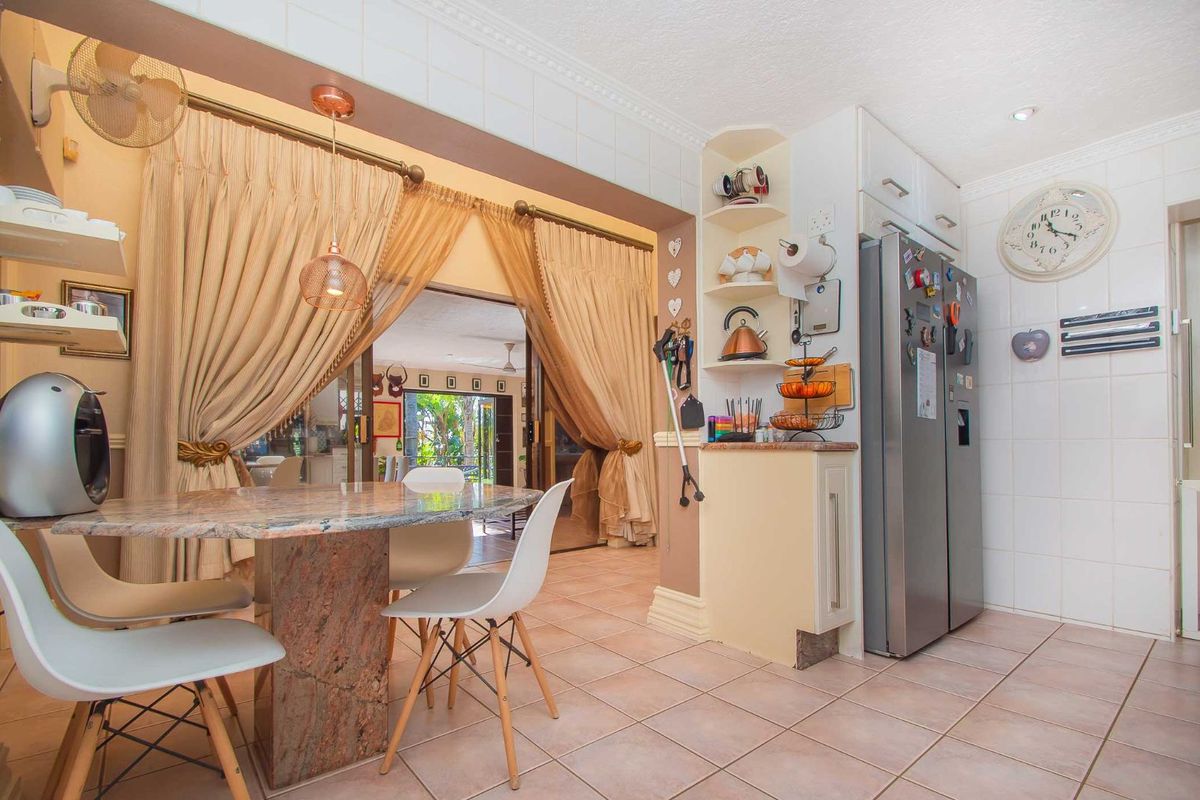 A kitchen and dining area featuring tiled flooring, built-in cabinetry, and a stone-topped dining table, with an open transition to the adjacent living space.