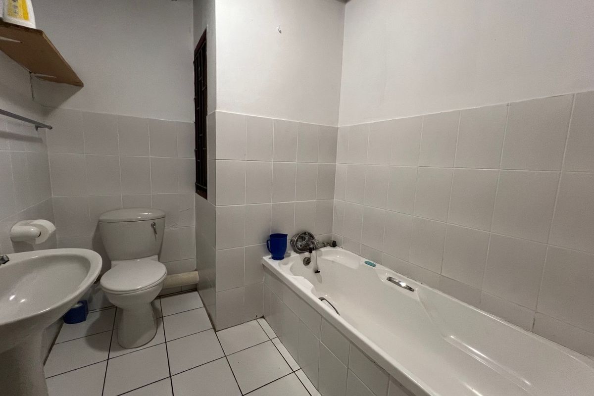 A functional bathroom featuring a white bathtub, pedestal sink, and toilet with tiled walls and flooring.