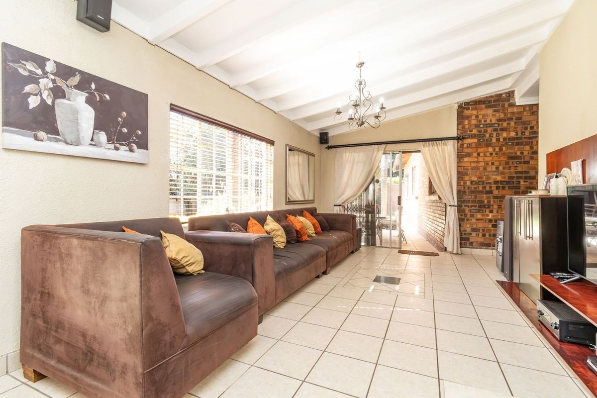 Spacious living room featuring exposed beam ceilings, a rustic brick feature wall, and large sliding glass doors providing access to the outdoor area.