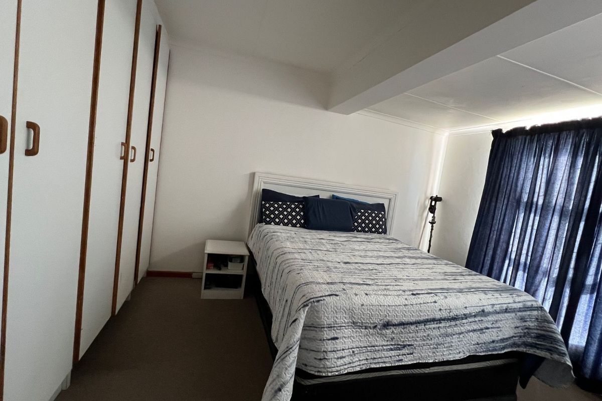 A bedroom featuring built-in cupboards and carpeted flooring, providing a functional space with neutral finishes.