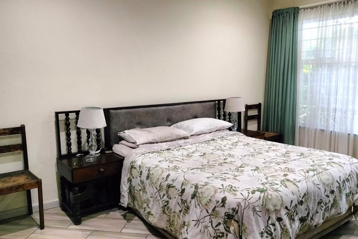 A well-lit bedroom featuring tiled flooring and floor-to-ceiling curtains, providing a neutral and functional space.
