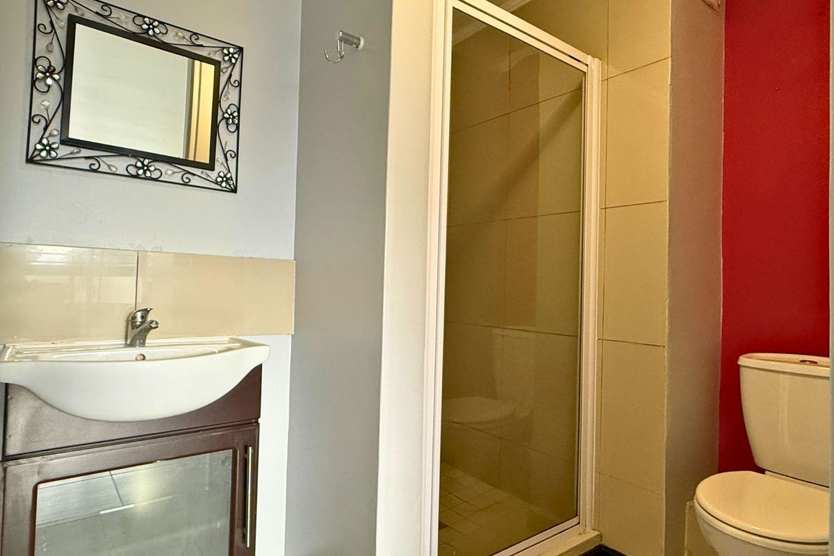 A functional bathroom featuring a vanity basin, a glass-enclosed shower, and a standard toilet with tiled wall finishes.