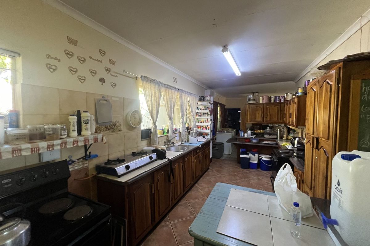 A dated kitchen featuring wooden cabinetry, tiled countertops, and ceramic floor tiles, offering a functional layout with ample storage space.