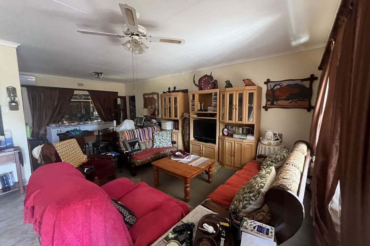 A spacious living room featuring a ceiling fan and tiled flooring, providing a comfortable area for relaxation and family gatherings.