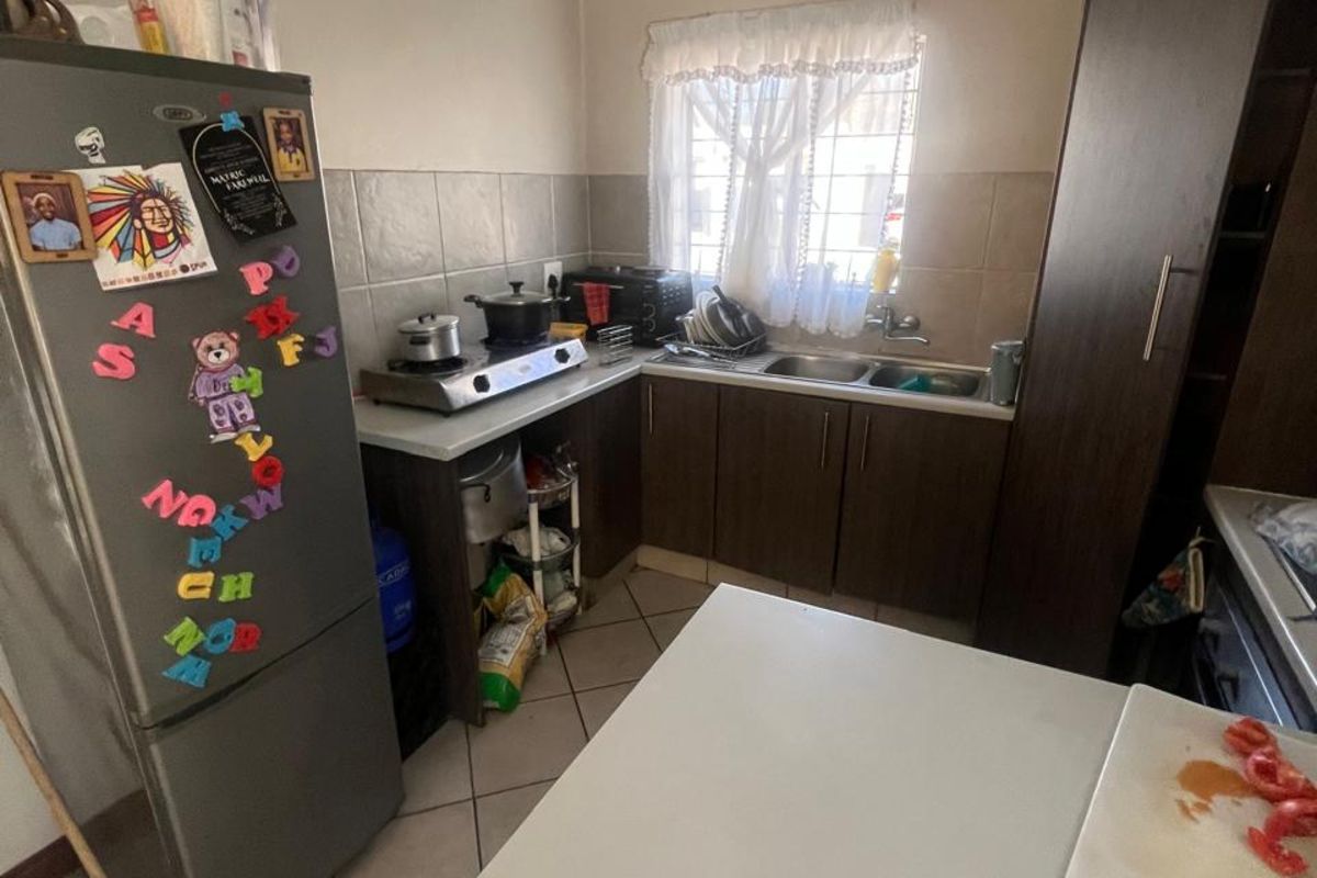 Compact kitchen featuring dark wood-look cabinetry, a stainless steel double sink, and tiled flooring, providing a functional workspace.