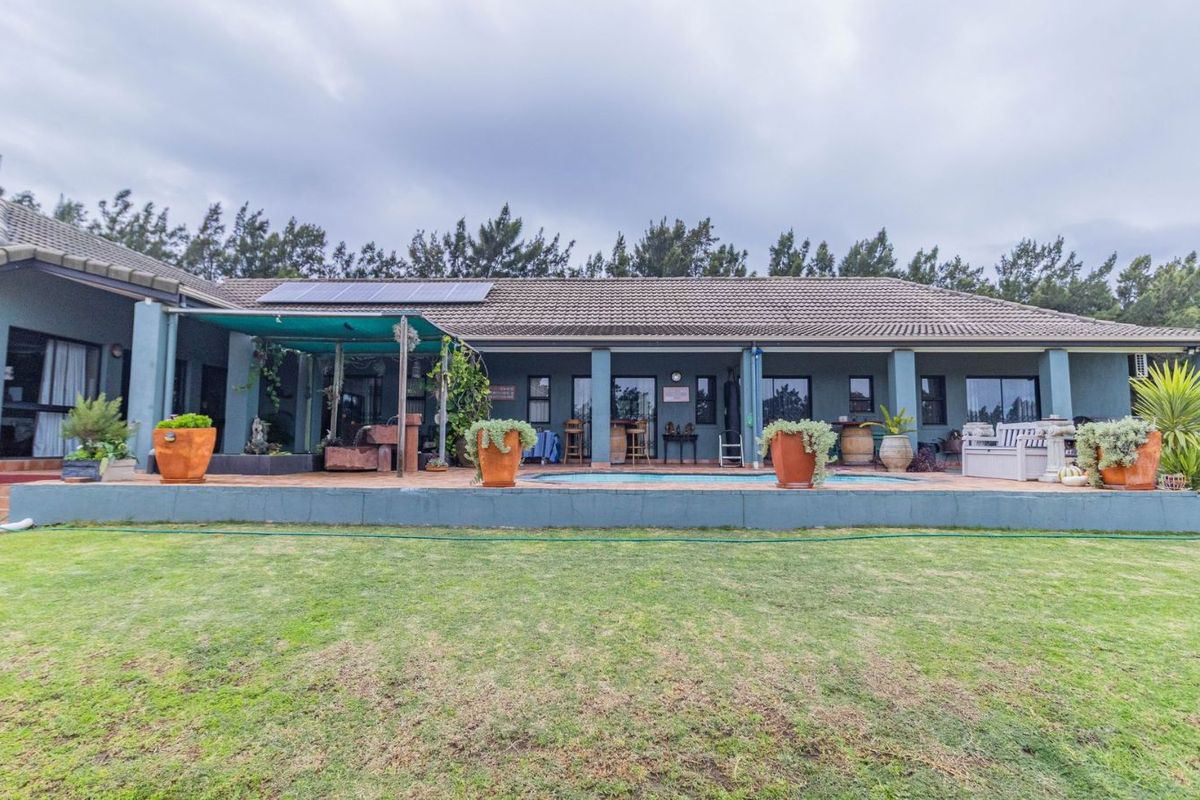 Rear view of the farmhouse featuring a covered patio, swimming pool, and solar panels installed on the tiled roof.