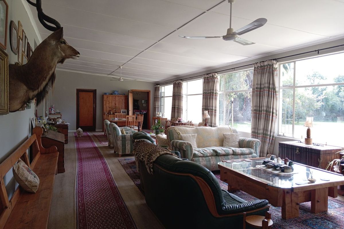 Spacious living area featuring large windows with garden views, ceiling fans, and traditional finishes, offering a comfortable and bright communal space.