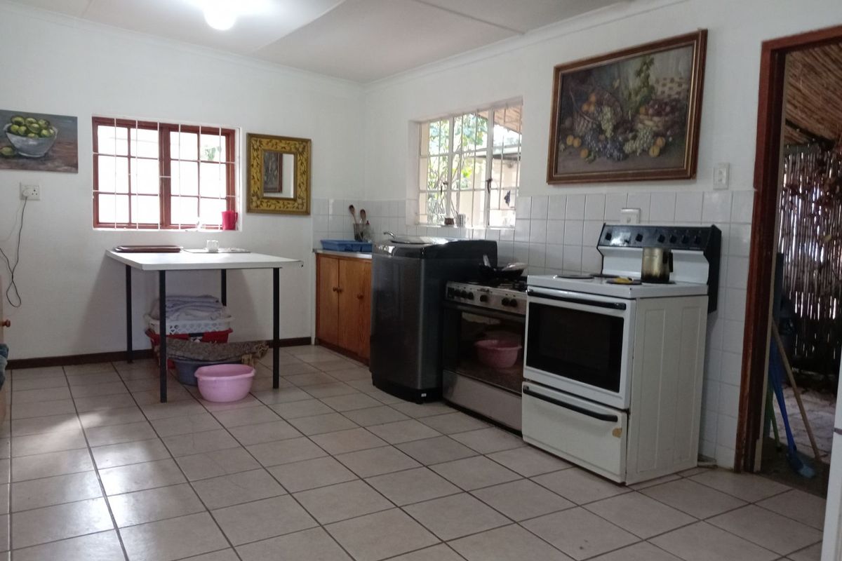A functional kitchen featuring tiled flooring, white wall tiles, built-in cabinetry, and a freestanding stove with an oven.