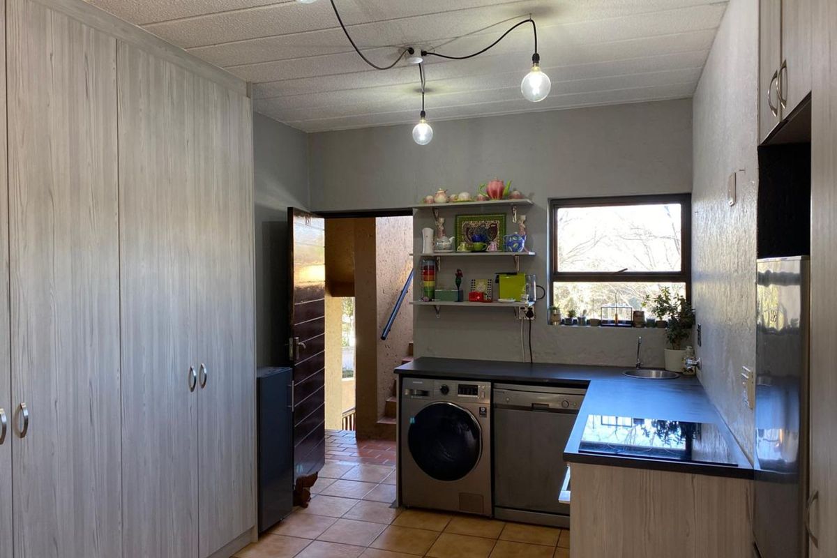 Functional kitchen featuring built-in cabinetry, dark countertops, integrated sink, and space for laundry appliances, with direct access to an exterior stairwell.