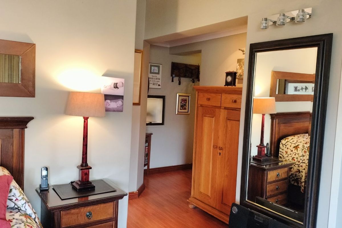 A bedroom featuring laminate flooring, a built-in wardrobe, and a hallway leading to adjacent living spaces.