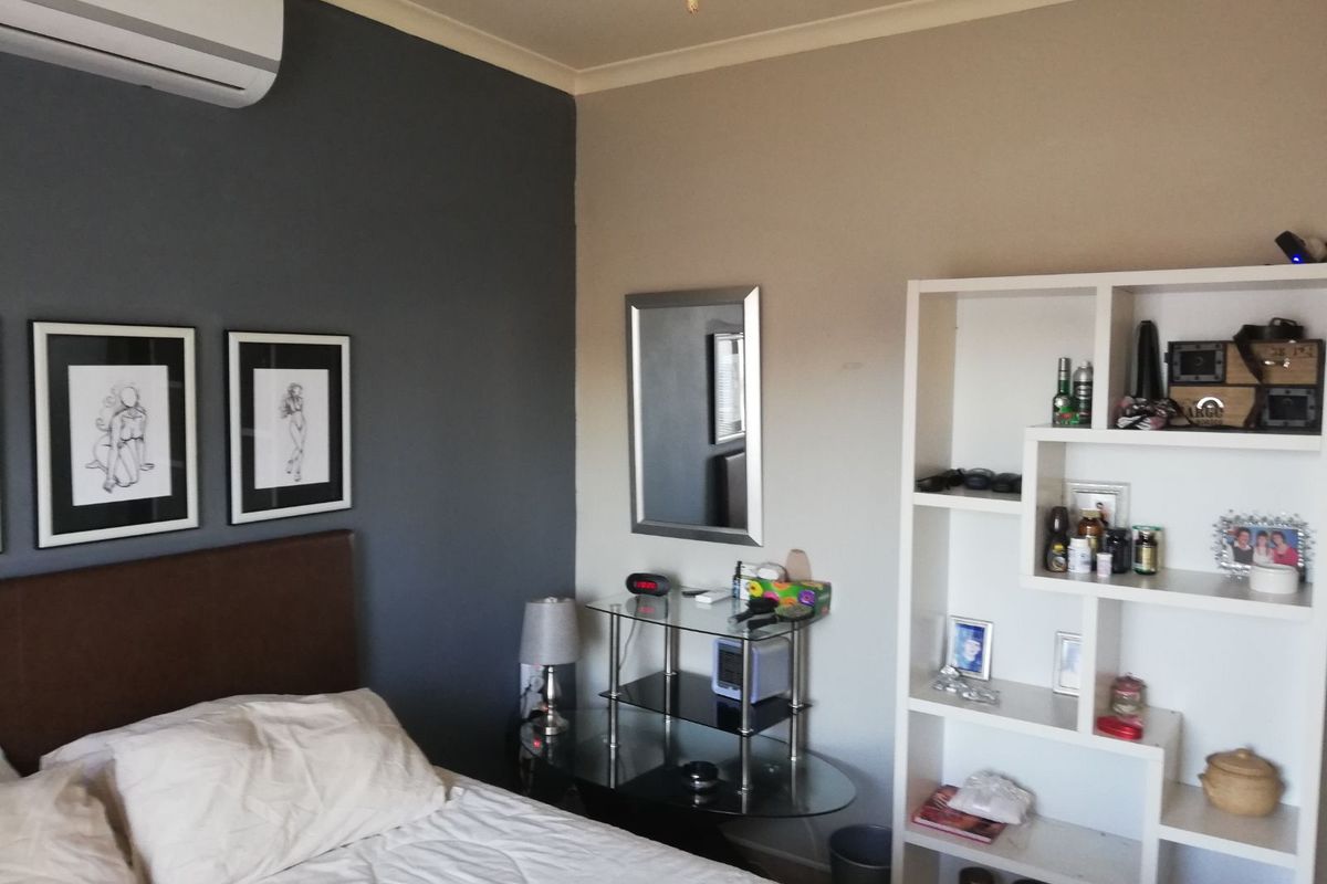A bedroom featuring a wall-mounted air conditioning unit and a neutral color scheme with a dark accent wall.