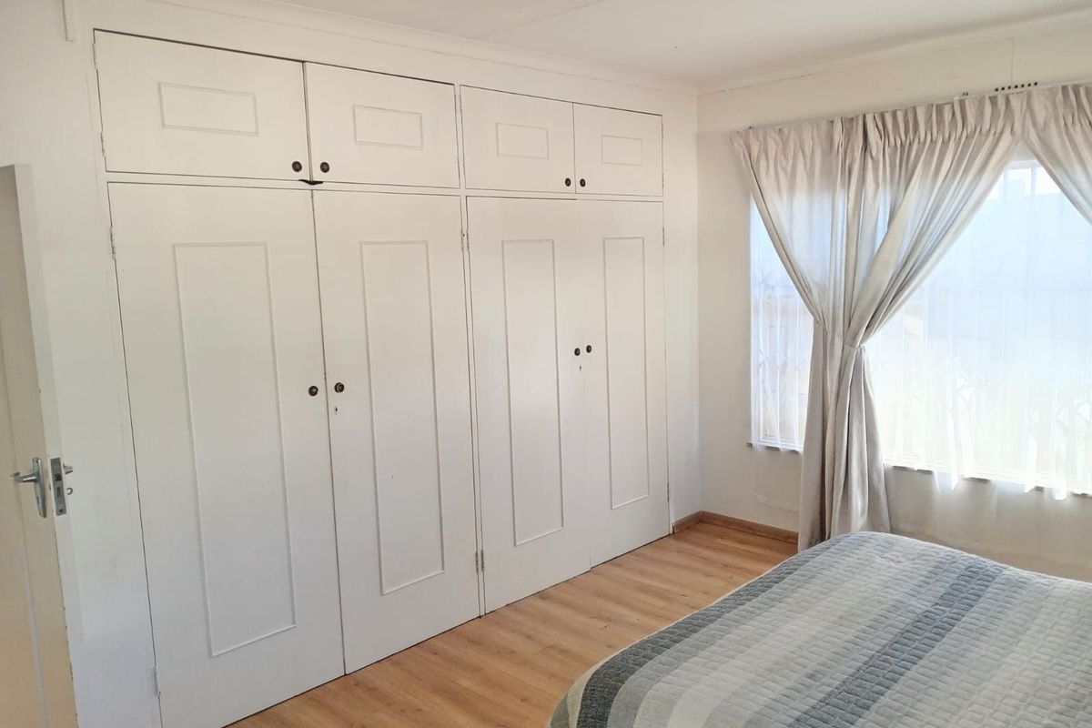 A bedroom featuring built-in floor-to-ceiling white cabinetry and light wood-look flooring, providing ample storage space.