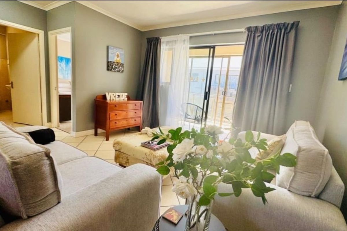 A comfortable living room featuring tiled flooring, neutral wall tones, and sliding glass doors that provide access to an outdoor balcony area.