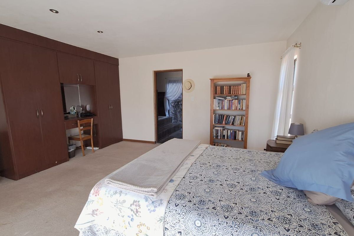 Spacious bedroom featuring extensive built-in dark wood cabinetry with an integrated vanity station and neutral wall finishes.