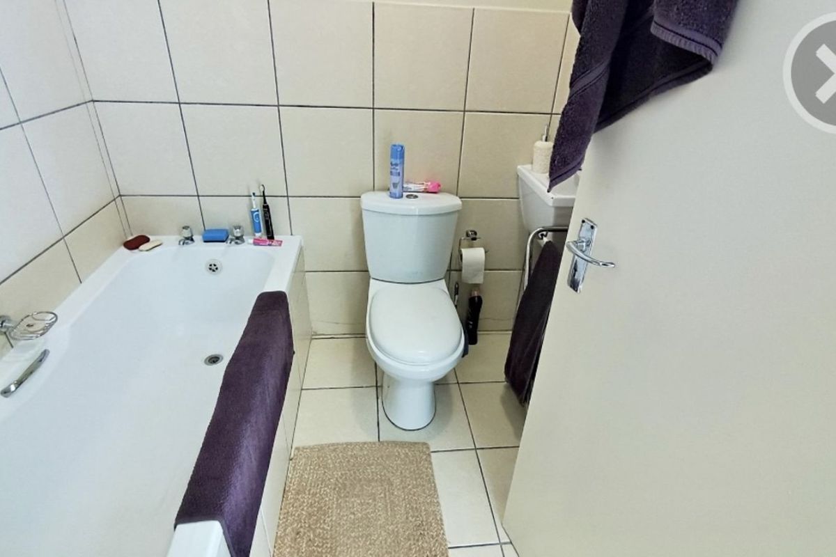 A functional bathroom featuring a standard bathtub, toilet, and tiled walls and flooring.