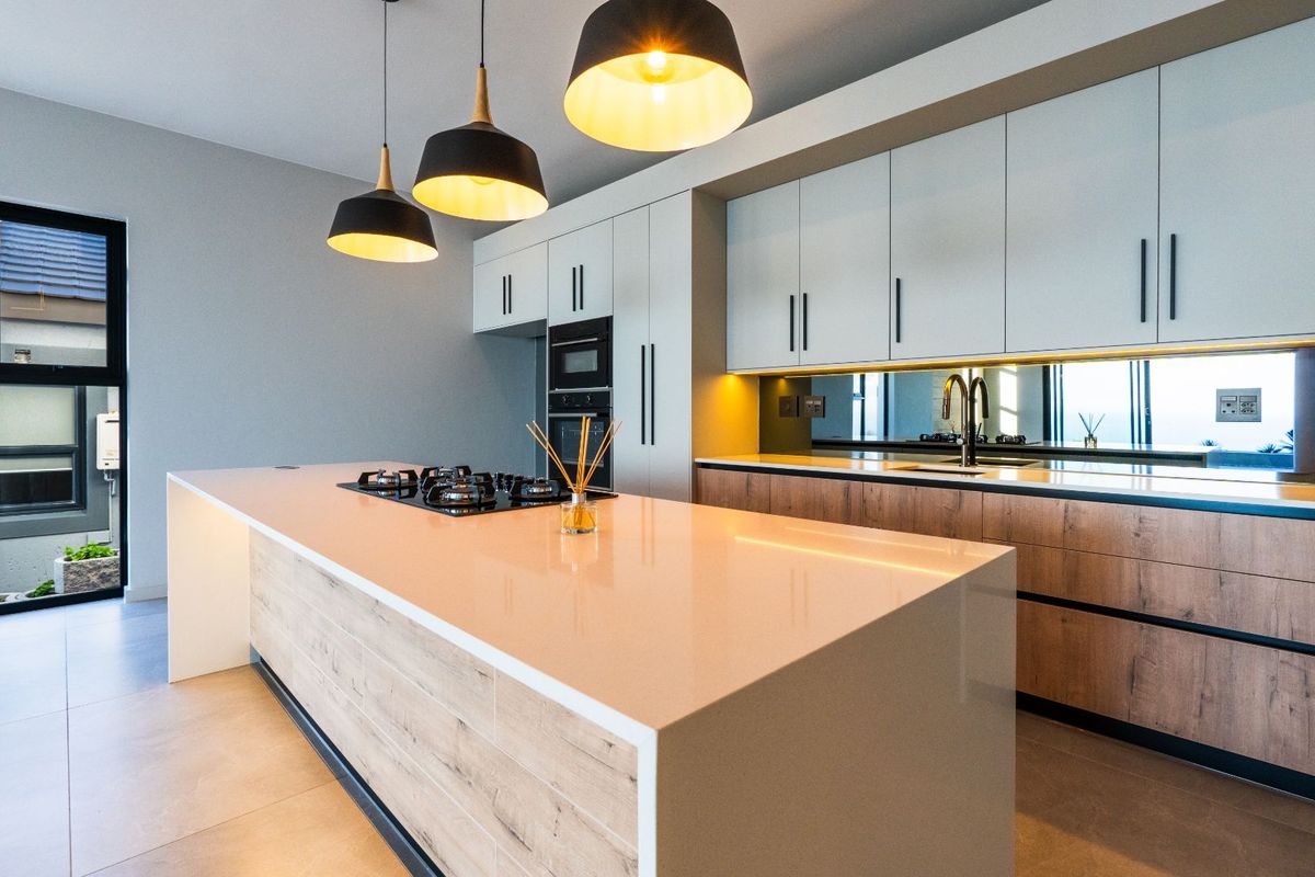 Modern kitchen featuring a large central island with a built-in gas hob, sleek cabinetry, integrated oven, and high-quality stone countertops.