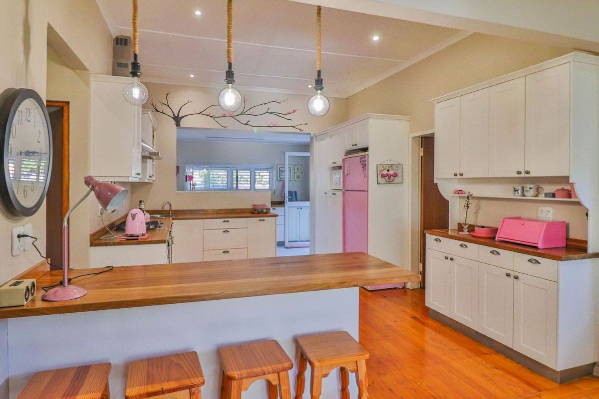A bright kitchen featuring white cabinetry, wooden countertops, a breakfast bar, and recessed lighting, creating a functional and inviting culinary space.