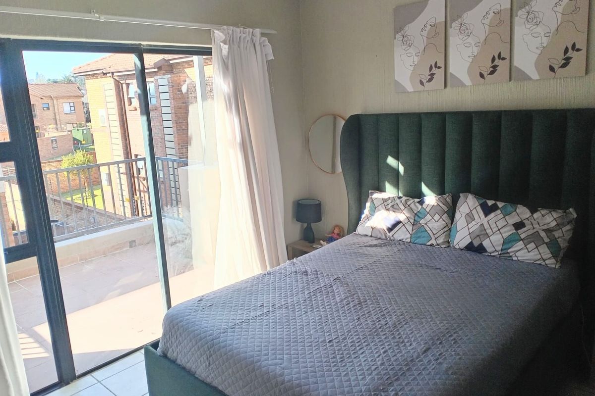 A well-lit bedroom featuring tiled flooring and large sliding glass doors that provide direct access to an attached balcony.