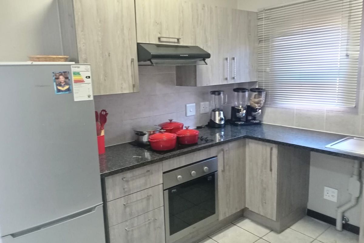 A functional kitchen featuring light wood-grain cabinetry, dark granite countertops, a built-in oven, extractor fan, and tiled flooring.