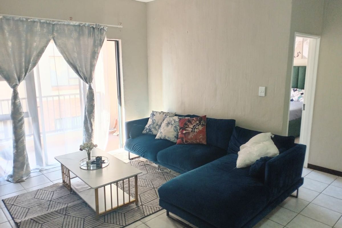 A bright living room featuring tiled flooring and a sliding glass door that opens to a balcony, providing natural light to the space.