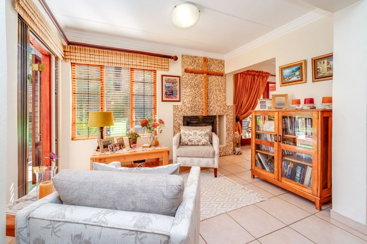 A cozy living room featuring a tiled floor, a stone-clad fireplace, and large windows with wooden blinds, offering a warm and inviting atmosphere.