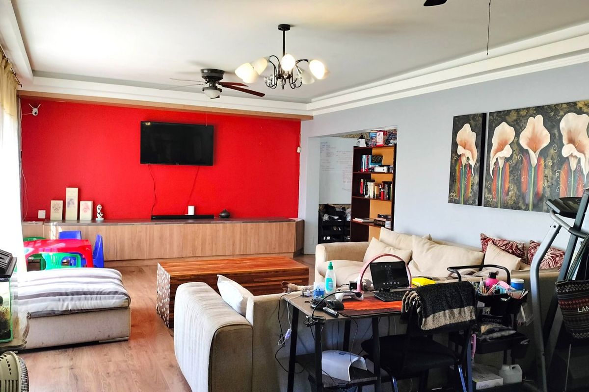 Spacious living room featuring a prominent red accent wall, built-in cabinetry, recessed ceiling detailing, and wood-look flooring.