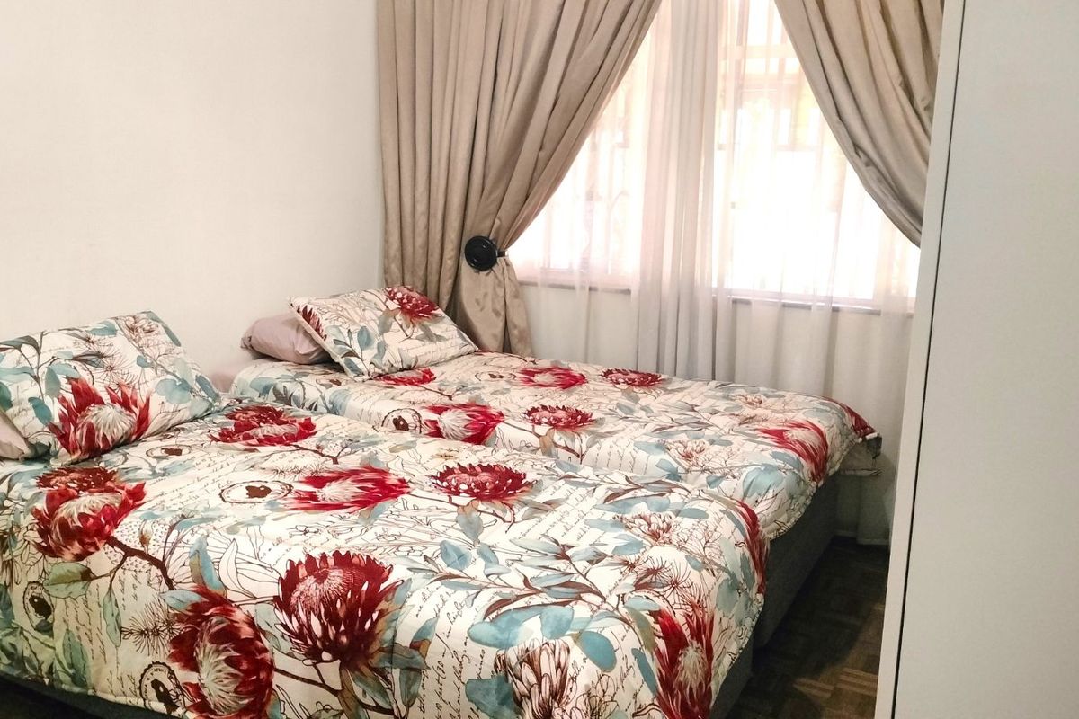 A bedroom featuring parquet flooring, a window with curtain tracks, and built-in wardrobe space.