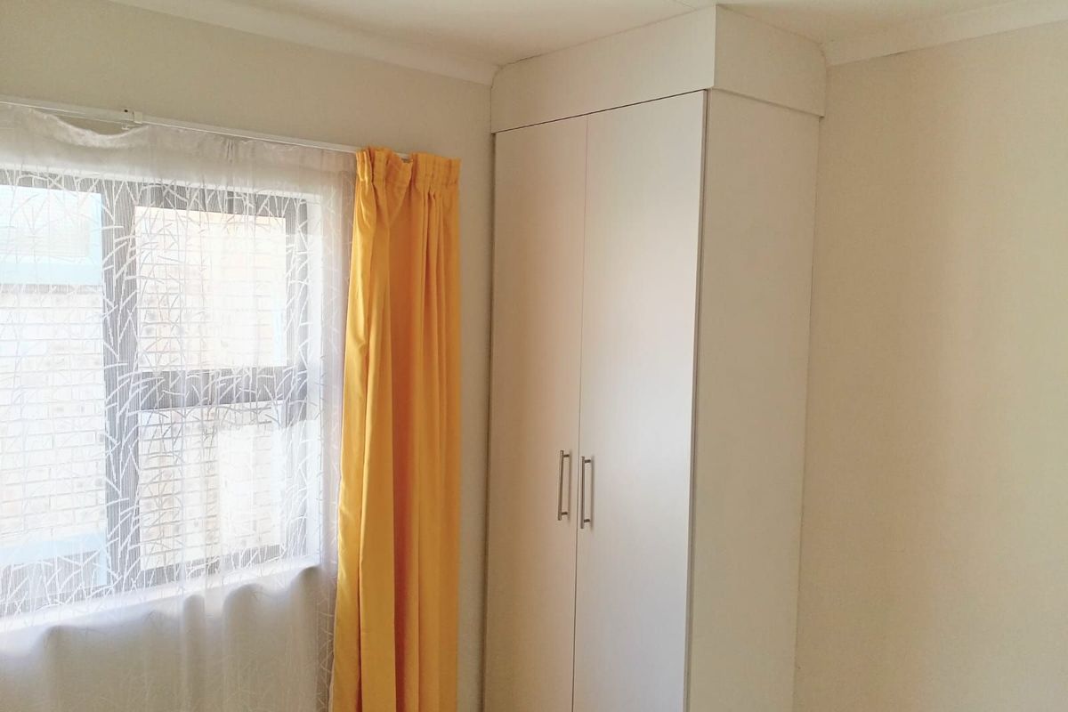 A bedroom featuring a built-in wardrobe and a window with natural light.