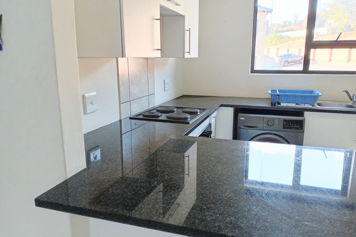 Modern kitchen featuring dark granite countertops, white cabinetry, a built-in electric hob, and an integrated space for a washing machine.