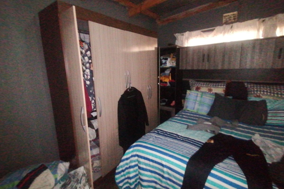 A bedroom featuring built-in cabinetry and an exposed ceiling structure, providing basic storage and sleeping space.