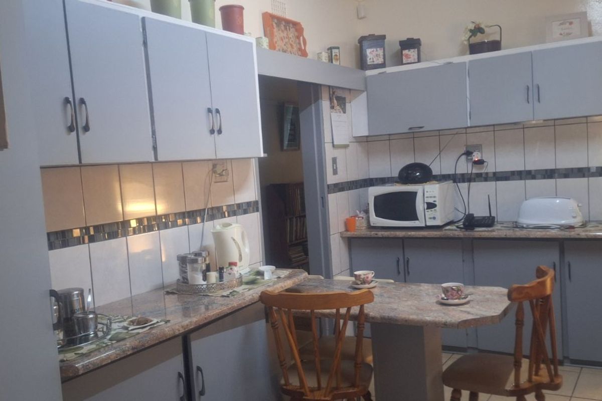 A functional kitchen featuring grey cabinetry, tiled backsplash, and a built-in breakfast nook area with stone-look countertops.