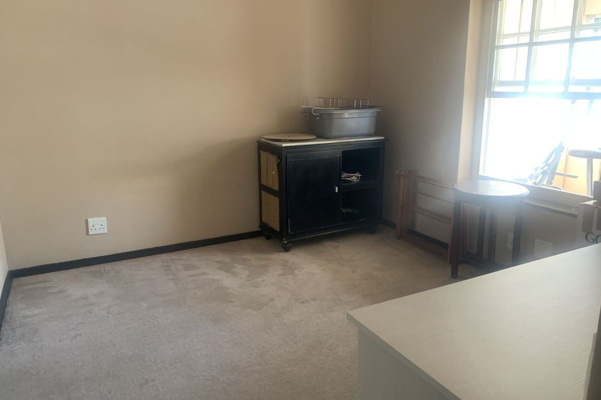A neutral-toned bedroom featuring fitted carpeting and a large window, providing a blank canvas for personalization.