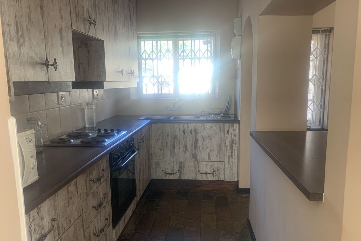 A functional kitchen featuring built-in cabinetry, a fitted oven and hob, and a double sink with a window view.
