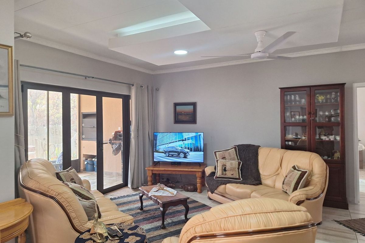 A comfortable living room featuring a recessed ceiling with integrated lighting, a ceiling fan, and large sliding glass doors leading to an outdoor patio area.