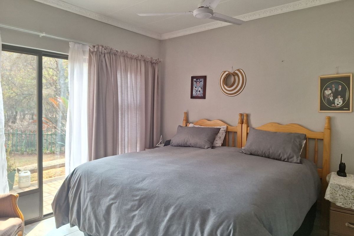 A well-lit bedroom featuring a ceiling fan, crown molding, and sliding glass doors that provide direct access to the outdoor patio area.