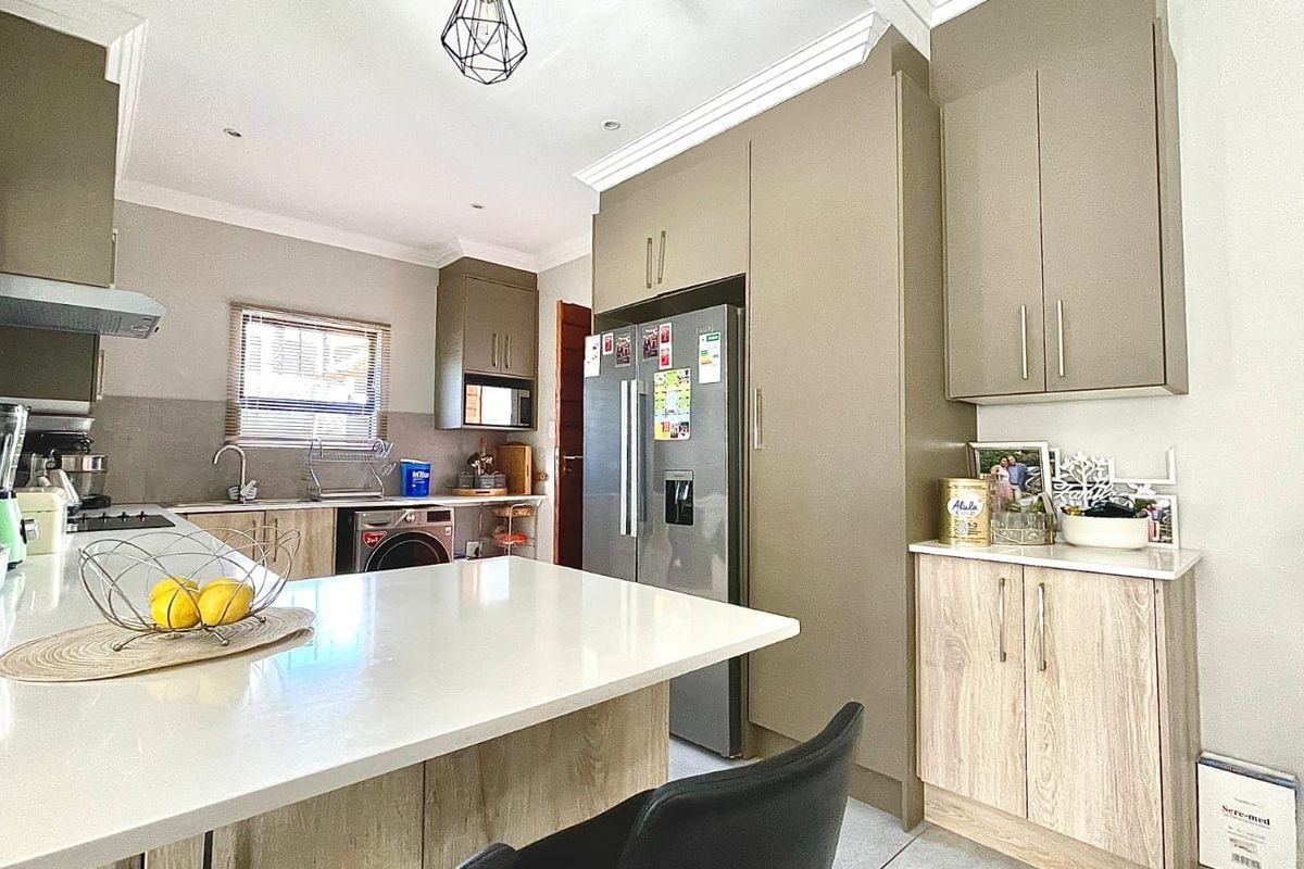 Modern kitchen featuring a central island, stone countertops, built-in cabinetry, and integrated appliances, offering a functional and contemporary cooking space.