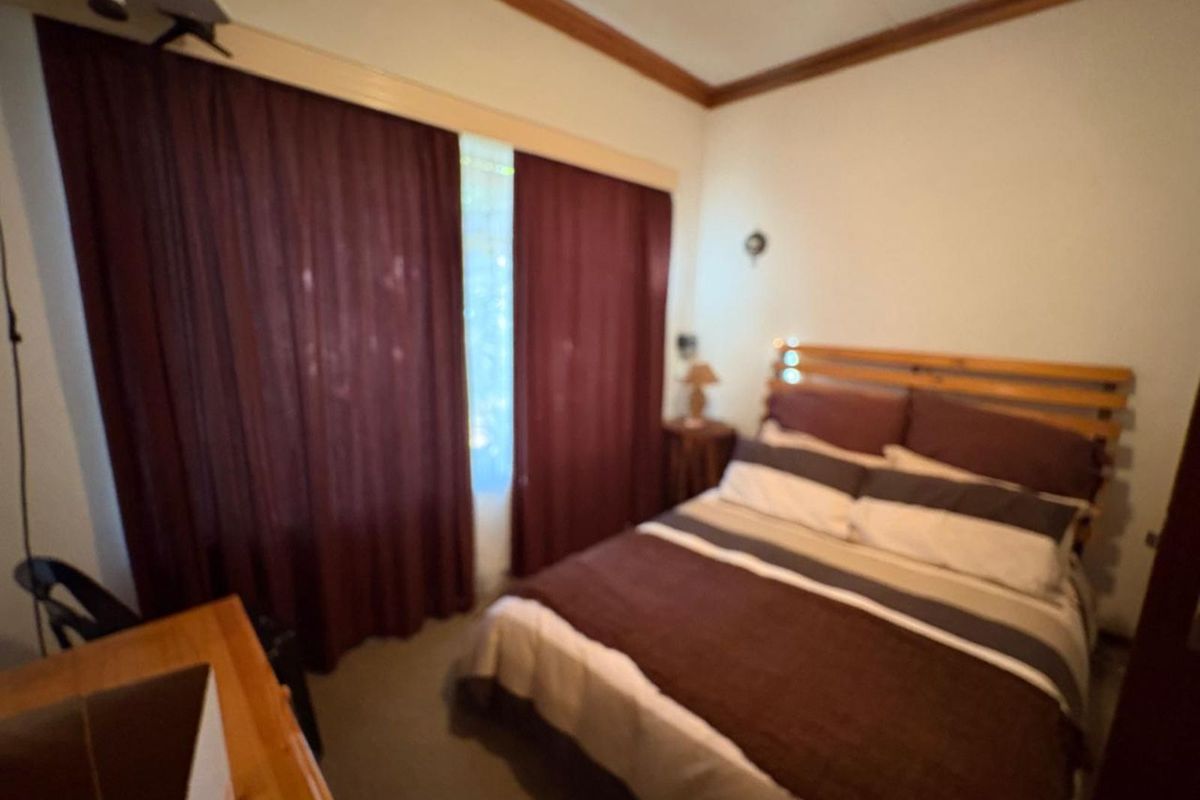A bedroom featuring neutral walls, carpeted flooring, and window treatments.